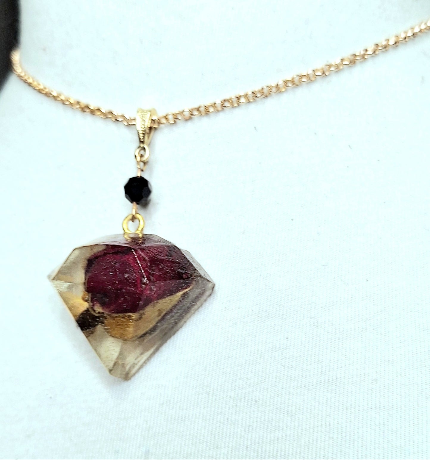 Mini Rosebud Encased in a Resin Jewel Pendant. A One-of-a-kind Pendant. Handmade. Strung on a gold chain with a gold bail and black crystal compliment.