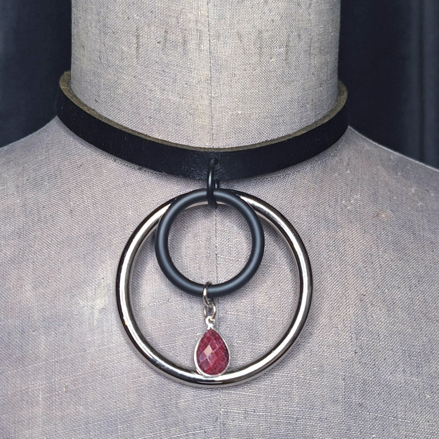 Chic Stone, Steel, & Silver oring collar. Black slender leather, 2" silver oring, & faceted Ruby teardrop.