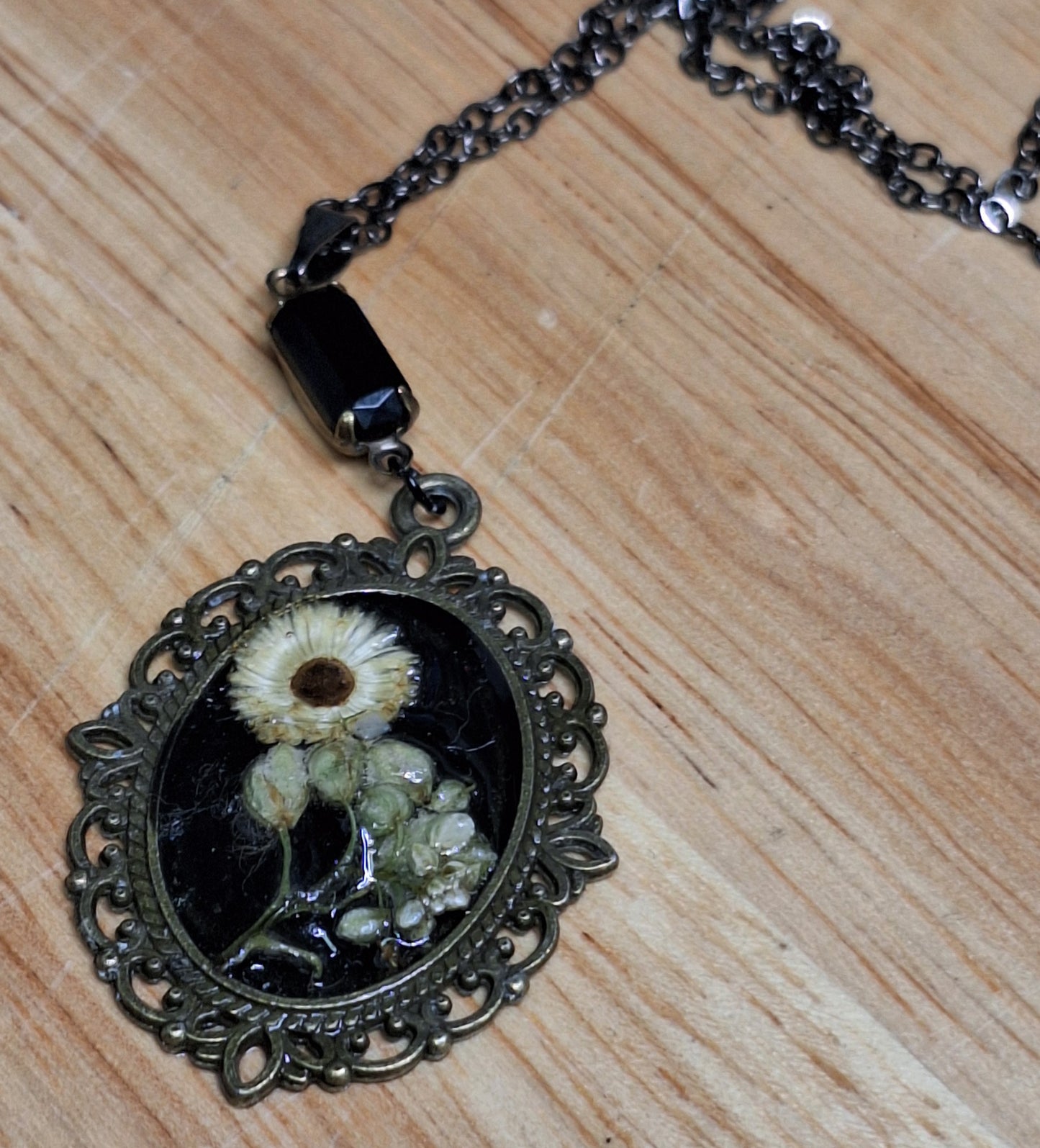 Antique Daisy pressed flower cameo necklace. Set in resin, real mini bouquet relief. Antique brass finish. Black crystal detail and chain.