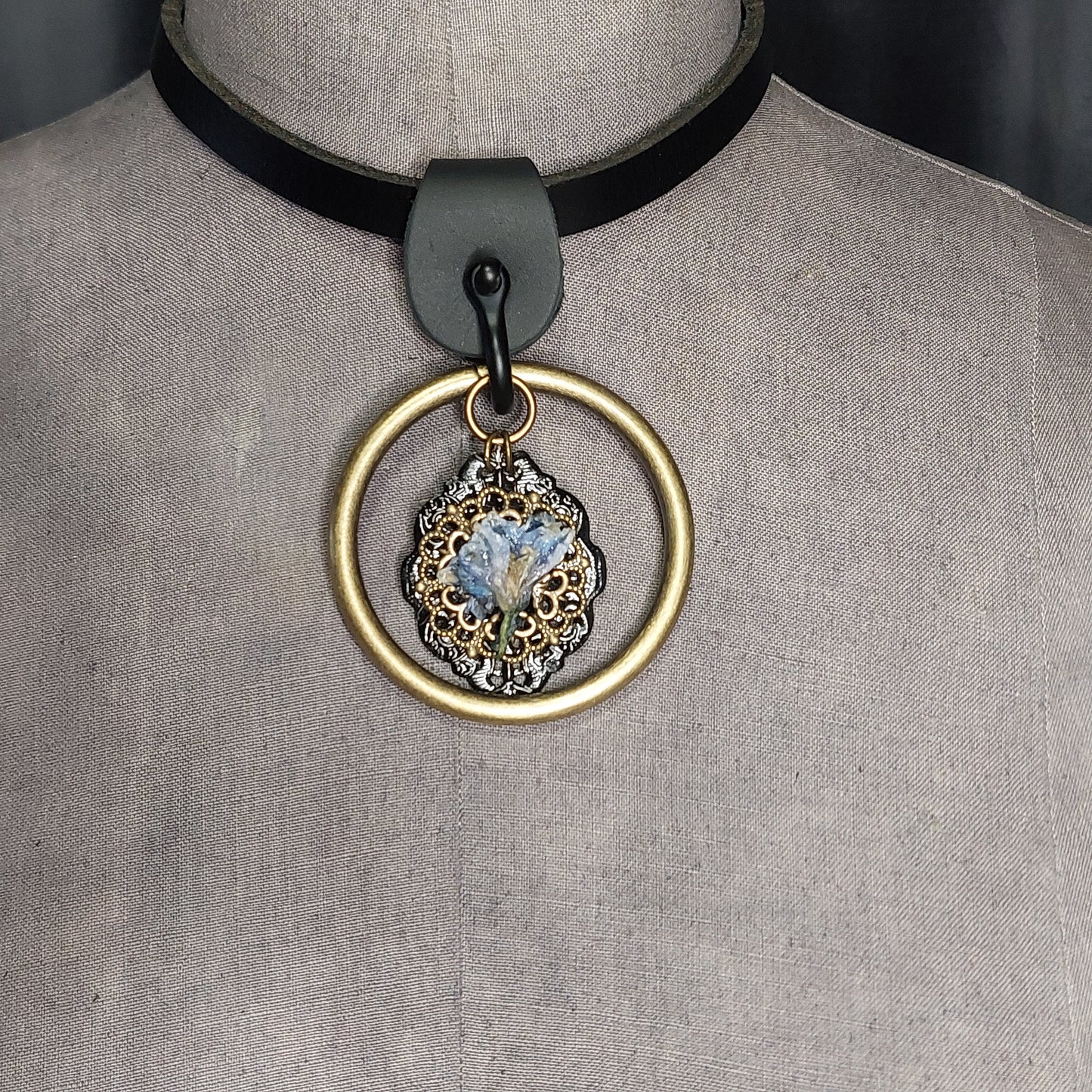 Nostaligia real blue flower encased in resin. Set on multifinish backdrop and suspended in an antique brass ring. Strung on a chic leather choker. Handmade.