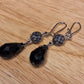 Black crystal teardrop and lavender faceted glass drop earrings. Silver hook closure.