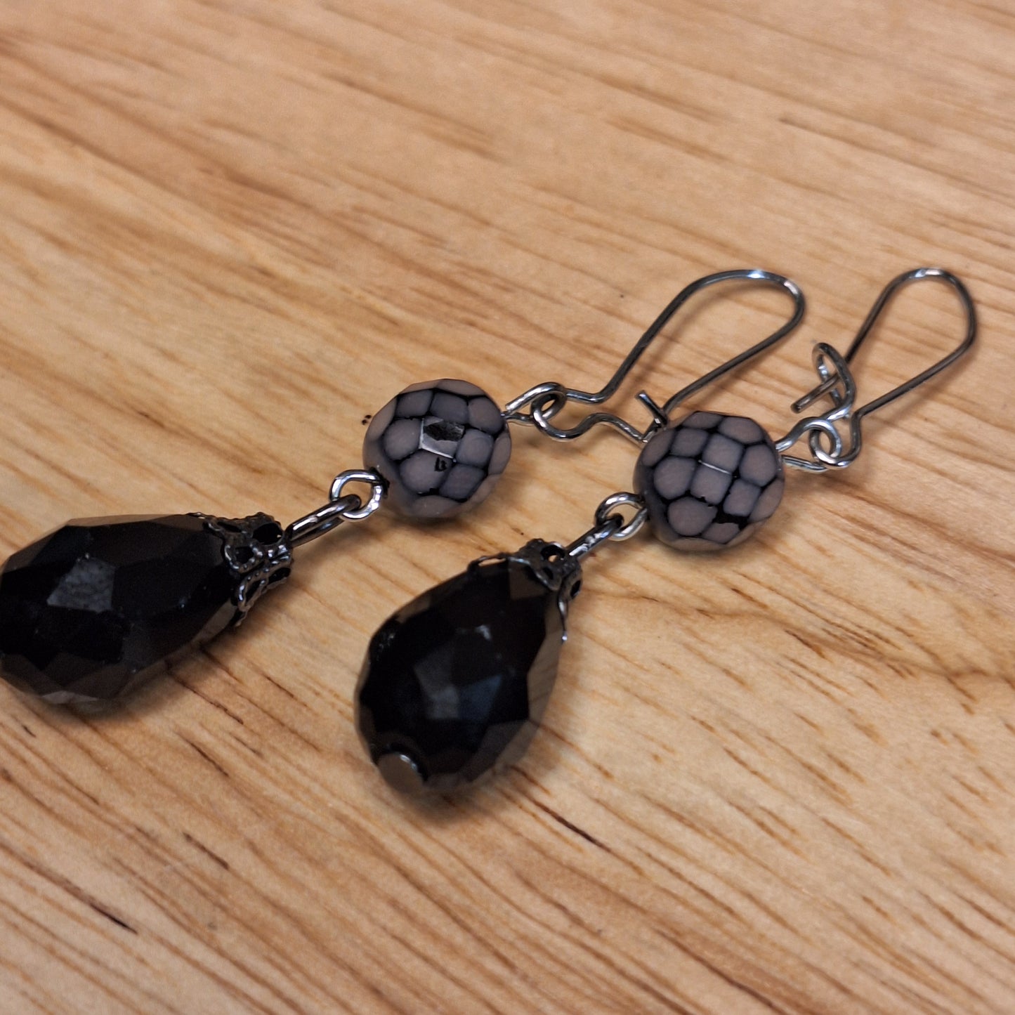 Black crystal teardrop and lavender faceted glass drop earrings. Silver hook closure.