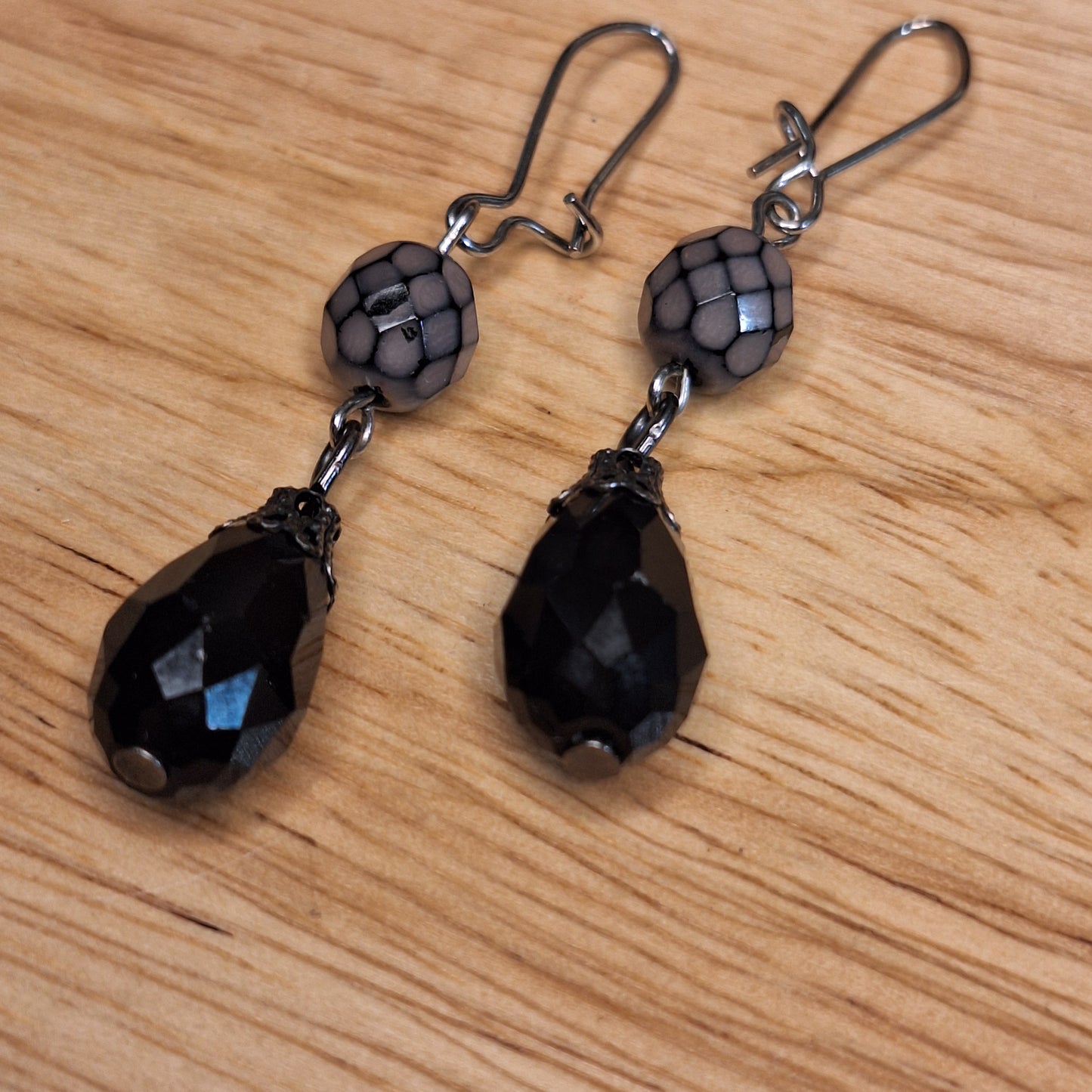 Black crystal teardrop and lavender faceted glass drop earrings. Silver hook closure.
