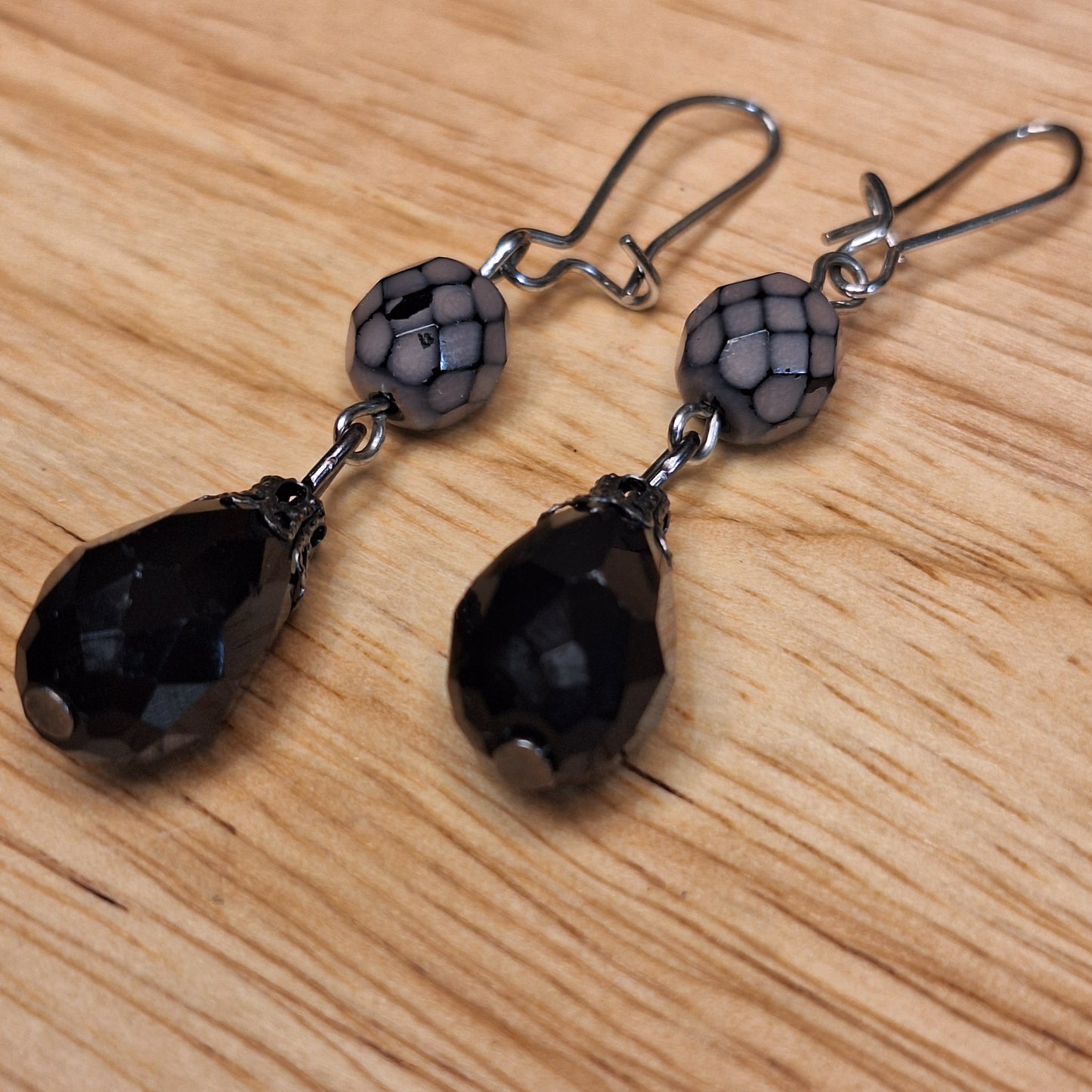 Black crystal teardrop and lavender faceted glass drop earrings. Silver hook closure.