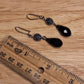 Black crystal teardrop and lavender faceted glass drop earrings. Silver hook closure.